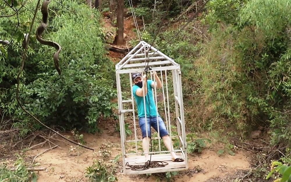 Sem ponte, moradores improvisam gaiola e se arriscam para atravessar córrego